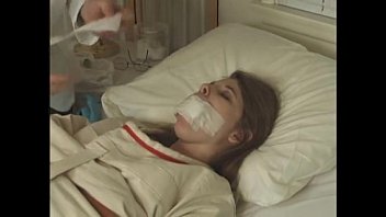 Pretty brunette in Straitjacket taped mouth tied to bed hospital