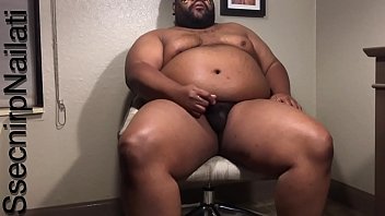 Black man in tan desk chair in hotel room.