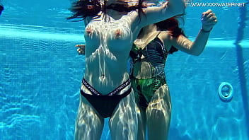 Gatas sensuais com peitos grandes nadando debaixo d'água na piscina