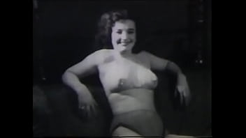 A mature lady with dark silky hair takes part in the filming of a 60s porn film