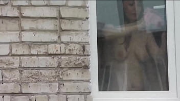 Desnudo en público. Desnudo. Exterior. Fuera de. El marido Sexy Frina está espiando a su hermana desde la ventana del coche cuando ella lava la ventana del apartamento sin bragas ni sostén.