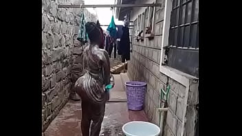 Обнаженная чернокожая принимает душ на улице