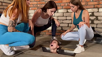 Drei Mädchen spucken einen im schmutzigen Keller gefangenen Sklaven an